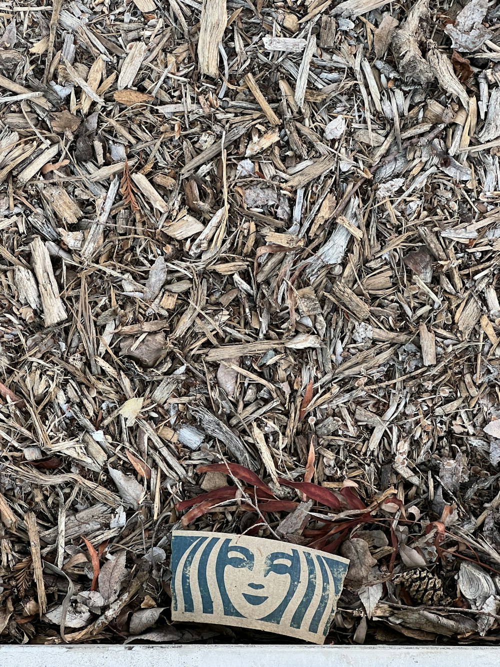 a blue and white vase sitting on top of a pile of wood chips
