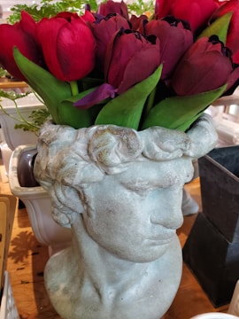 A sleek marble table vase holding fresh flowers on a wooden table.