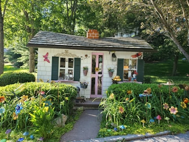Small cottage with a welcoming porch and blooming flowers nearby.