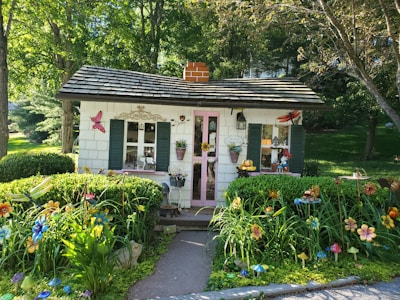 Seaside cottage with colorful shutters and blooming flowers.