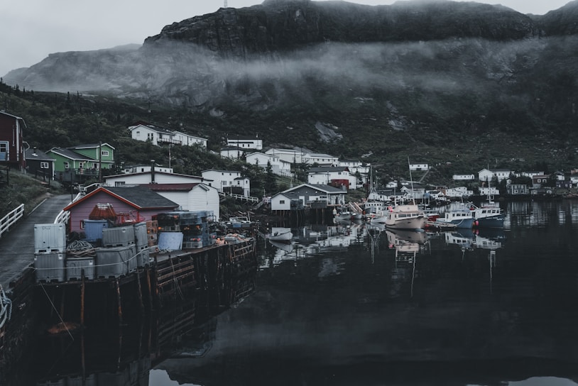 A serene coastal village at dawn, with soft light illuminating weathered stone cottages and calm sea.