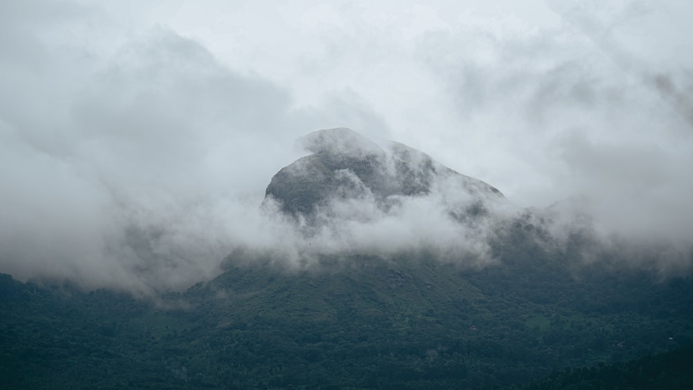 a mountain covered in clouds with a boat in the foreground