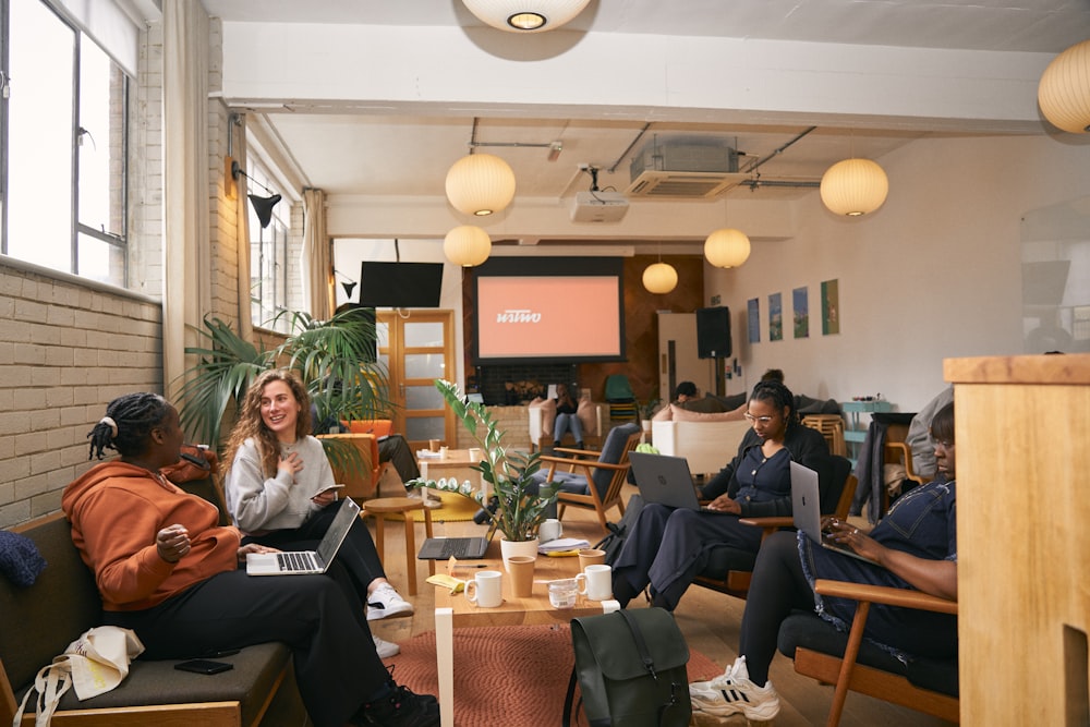 a group of people sitting in a room with laptops