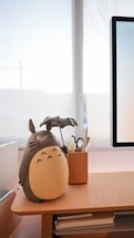 A cozy workspace with ceramic anime figurines displayed on shelves and a laptop open for customer messages.