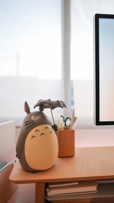 Dark slate grey blowbuddy on a minimalist office desk, with airflow visible through a light fabric fluttering softly in front.