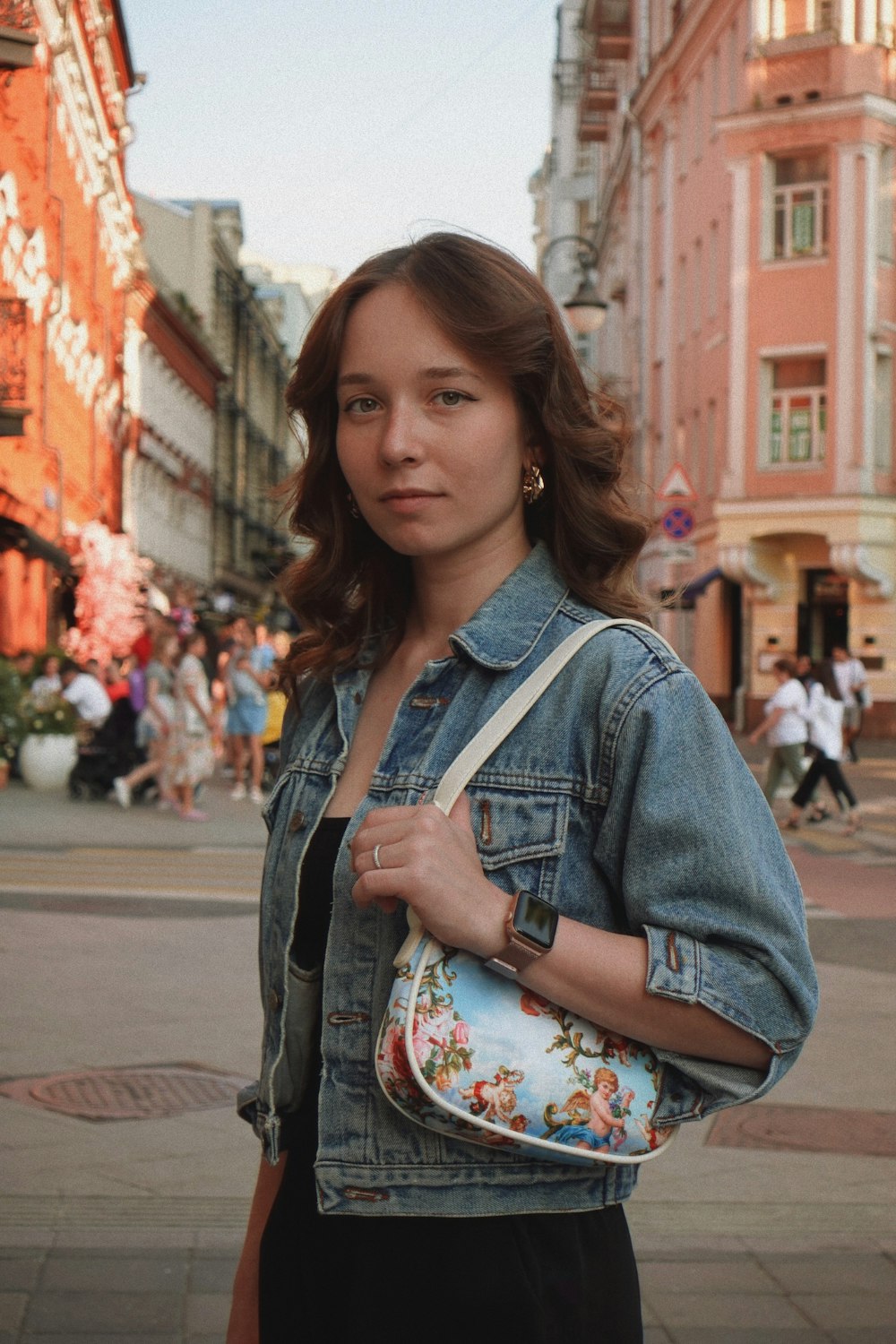 a woman standing on a street holding a purse