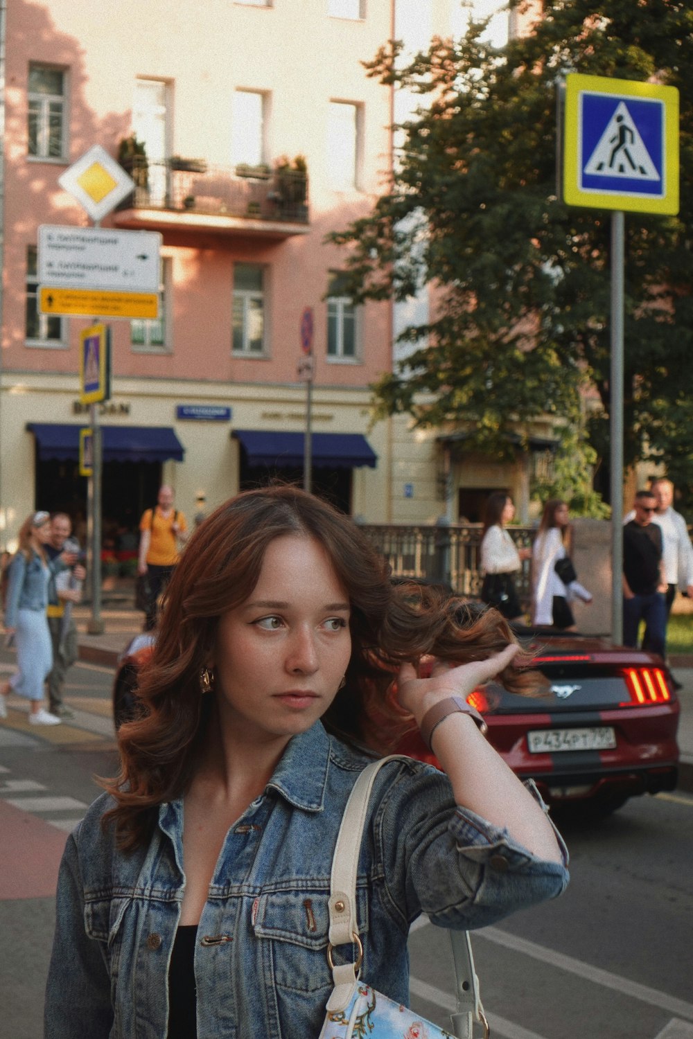 a woman in a denim jacket is walking down the street