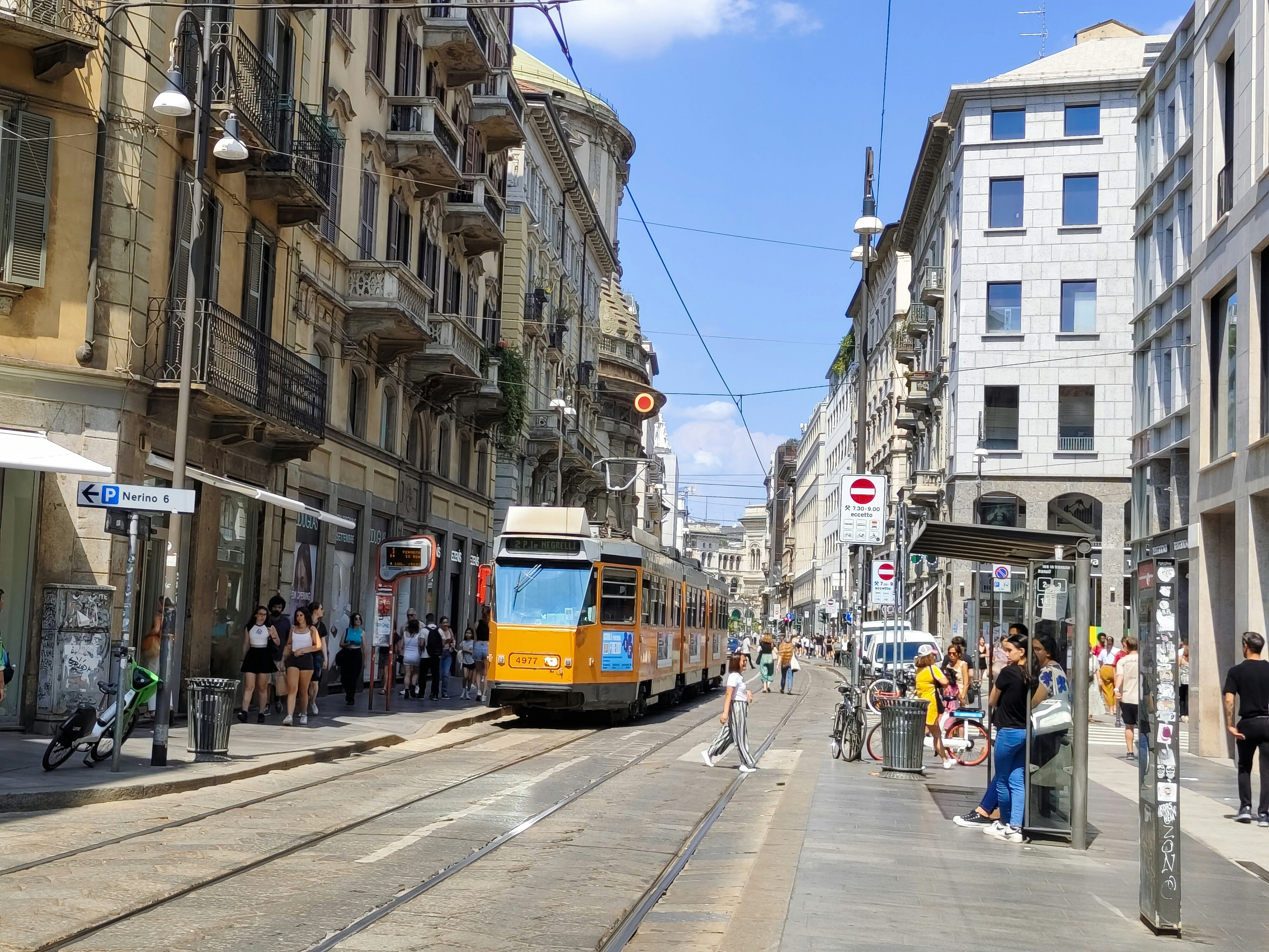 a yellow train traveling down a street next to tall buildings, 