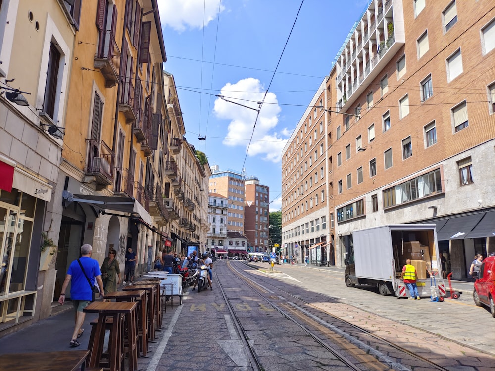 a city street with people walking and sitting on benches