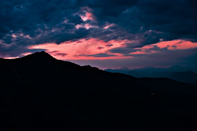 A rugged mountain landscape under a twilight sky with deep blues and purples