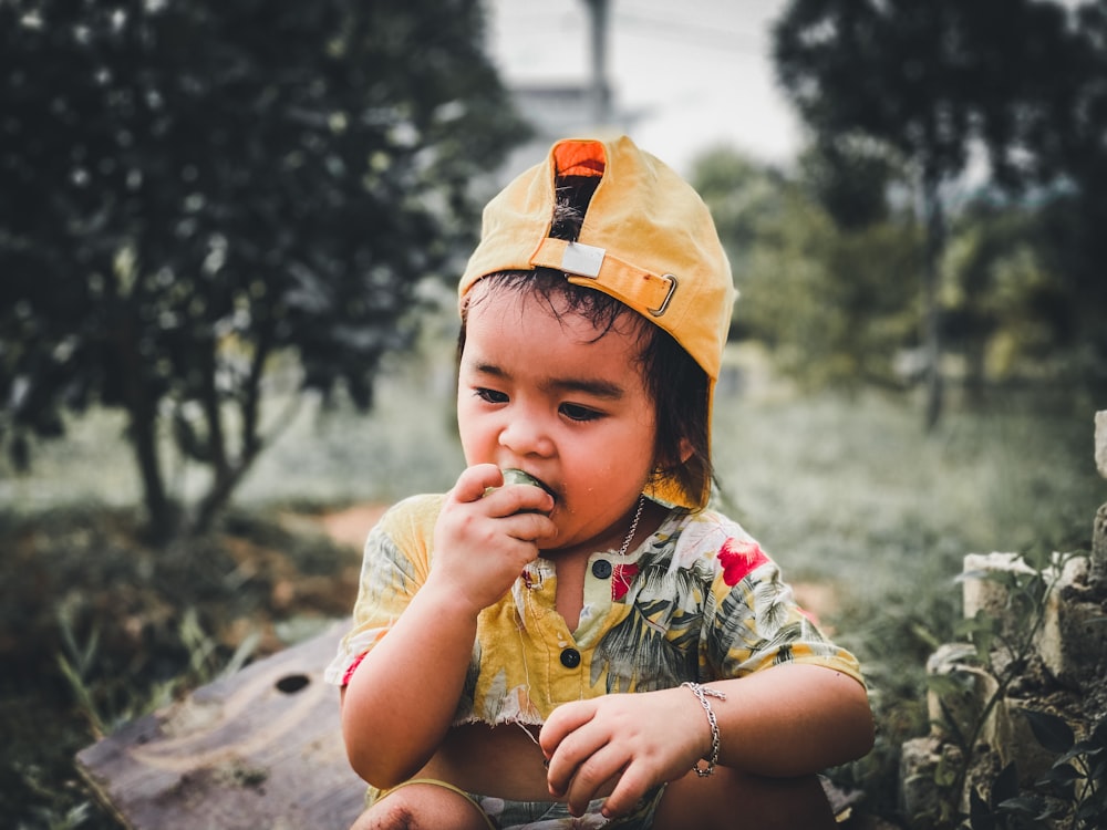 a small child wearing a yellow hat and eating something