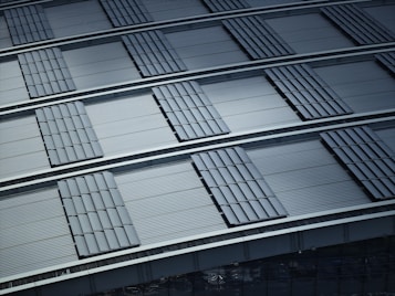 A pattern of overlapping metallic panels creates a structured and orderly composition. The panels have a corrugated texture that adds depth and dimension. The overall impression is of industrial design with precise alignment and repetitive shapes.