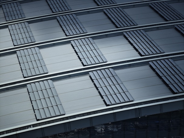 A pattern of overlapping metallic panels creates a structured and orderly composition. The panels have a corrugated texture that adds depth and dimension. The overall impression is of industrial design with precise alignment and repetitive shapes.