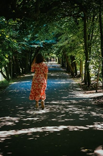 a woman walking down a tree lined road