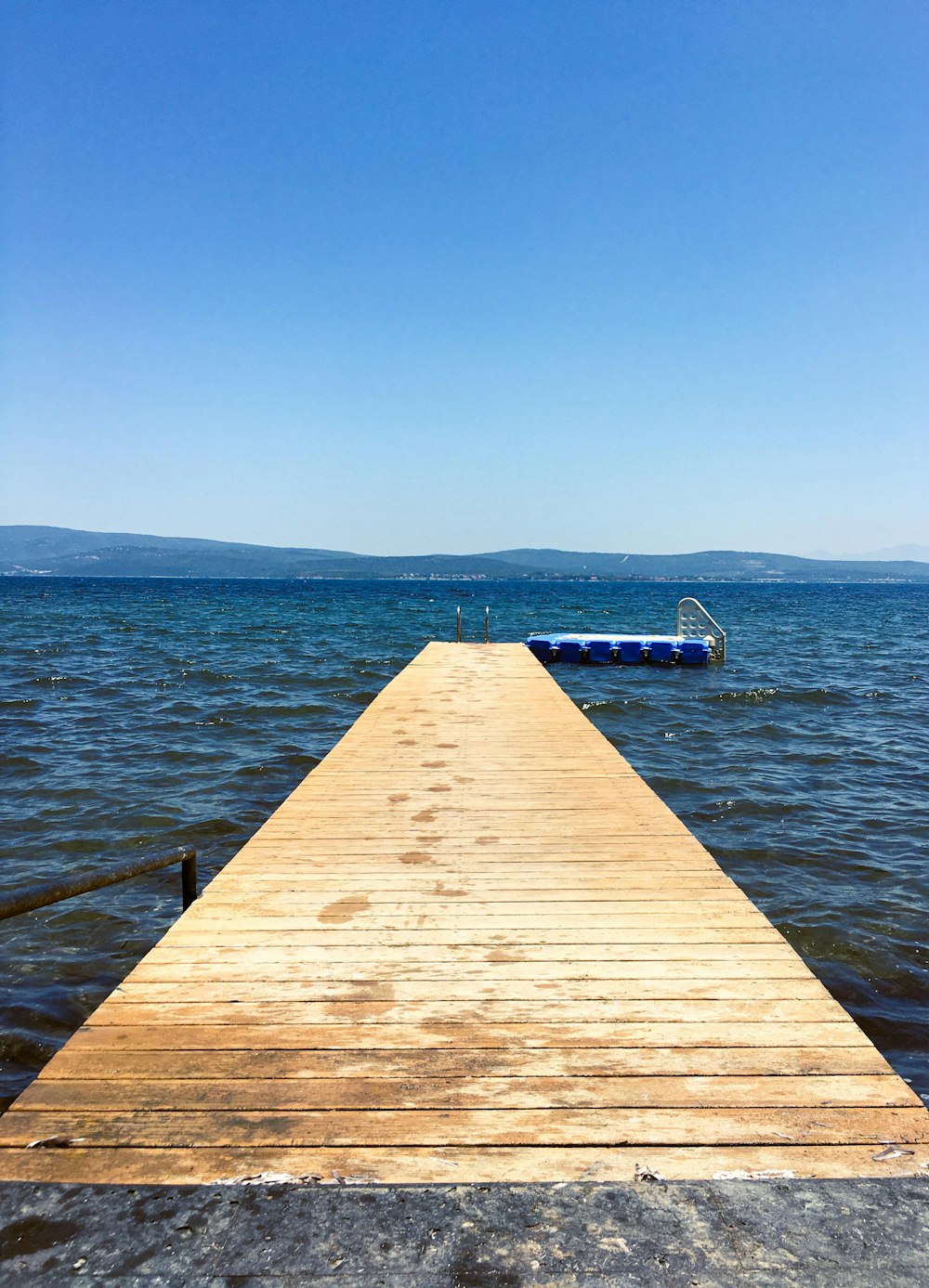 a wooden dock extending into the ocean with a boat in the distance