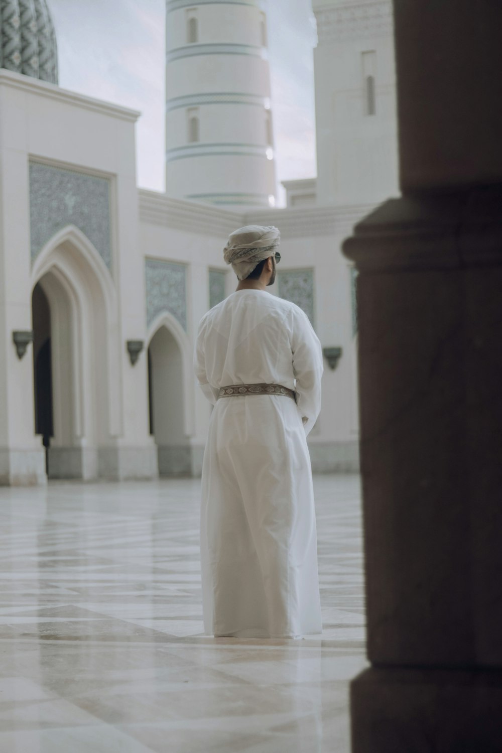 a man in a white outfit standing in front of a building