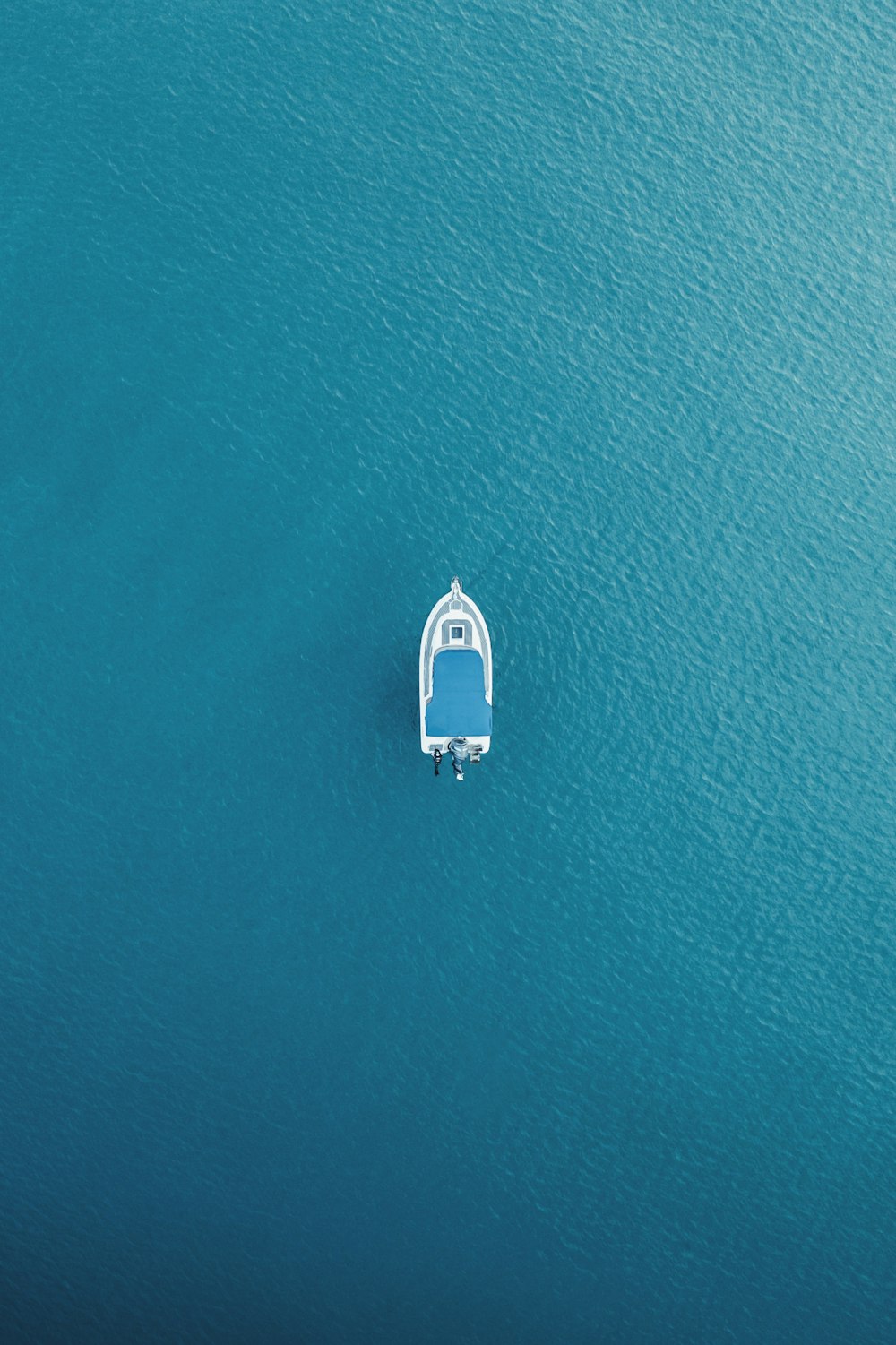 an aerial view of a small boat in the middle of the ocean