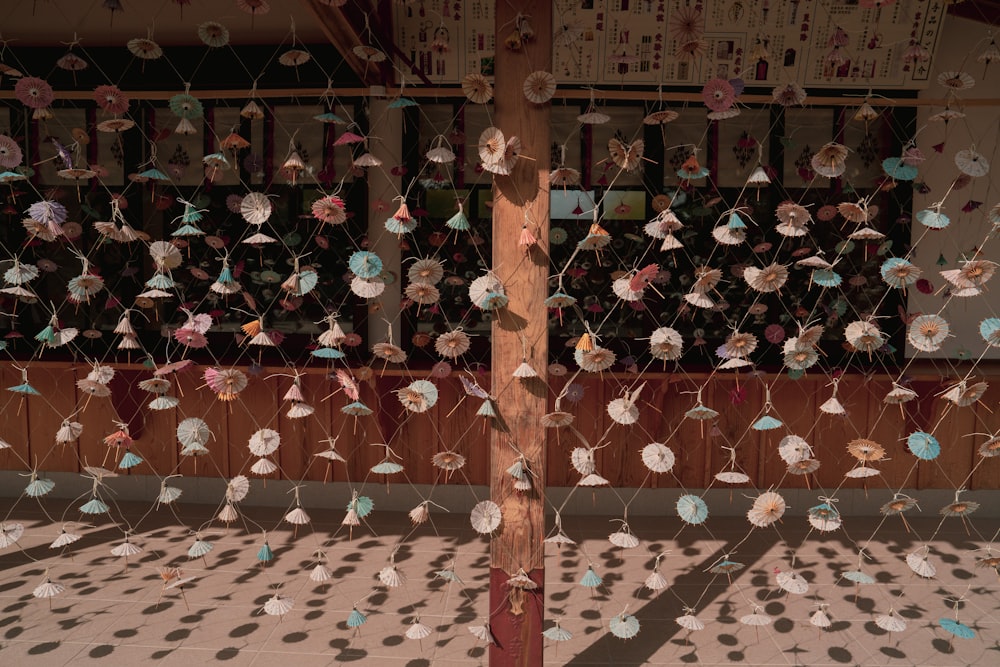 a wooden pole sitting in front of a wall covered in paper flowers