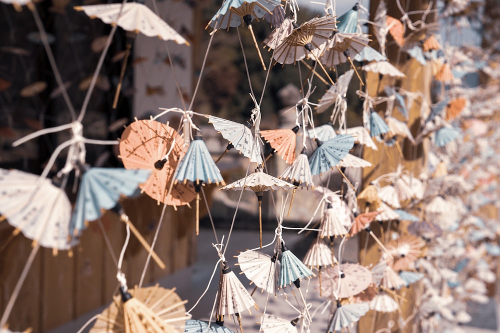 a bunch of paper umbrellas hanging on a fence