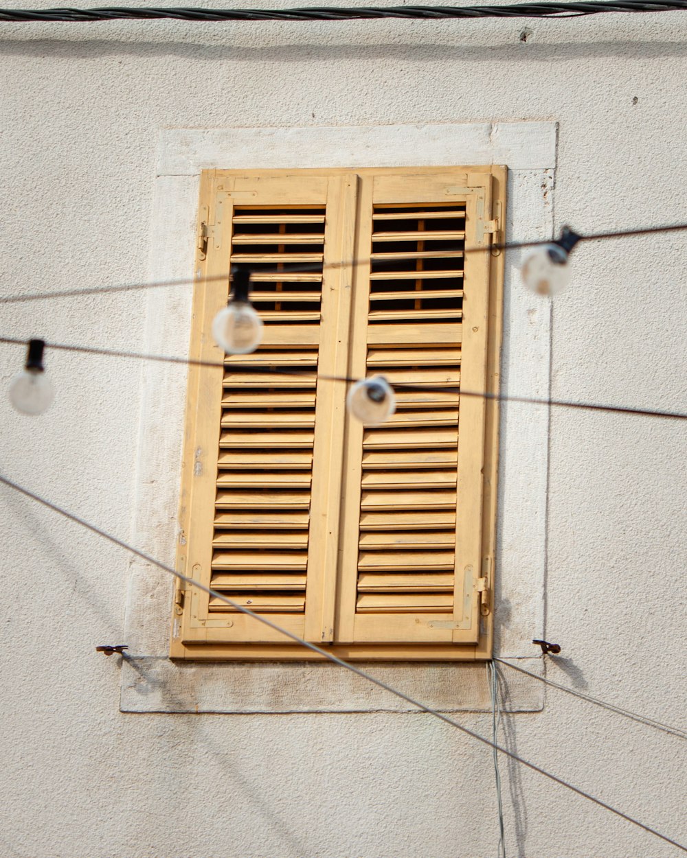 a window with wooden shutters on a white wall