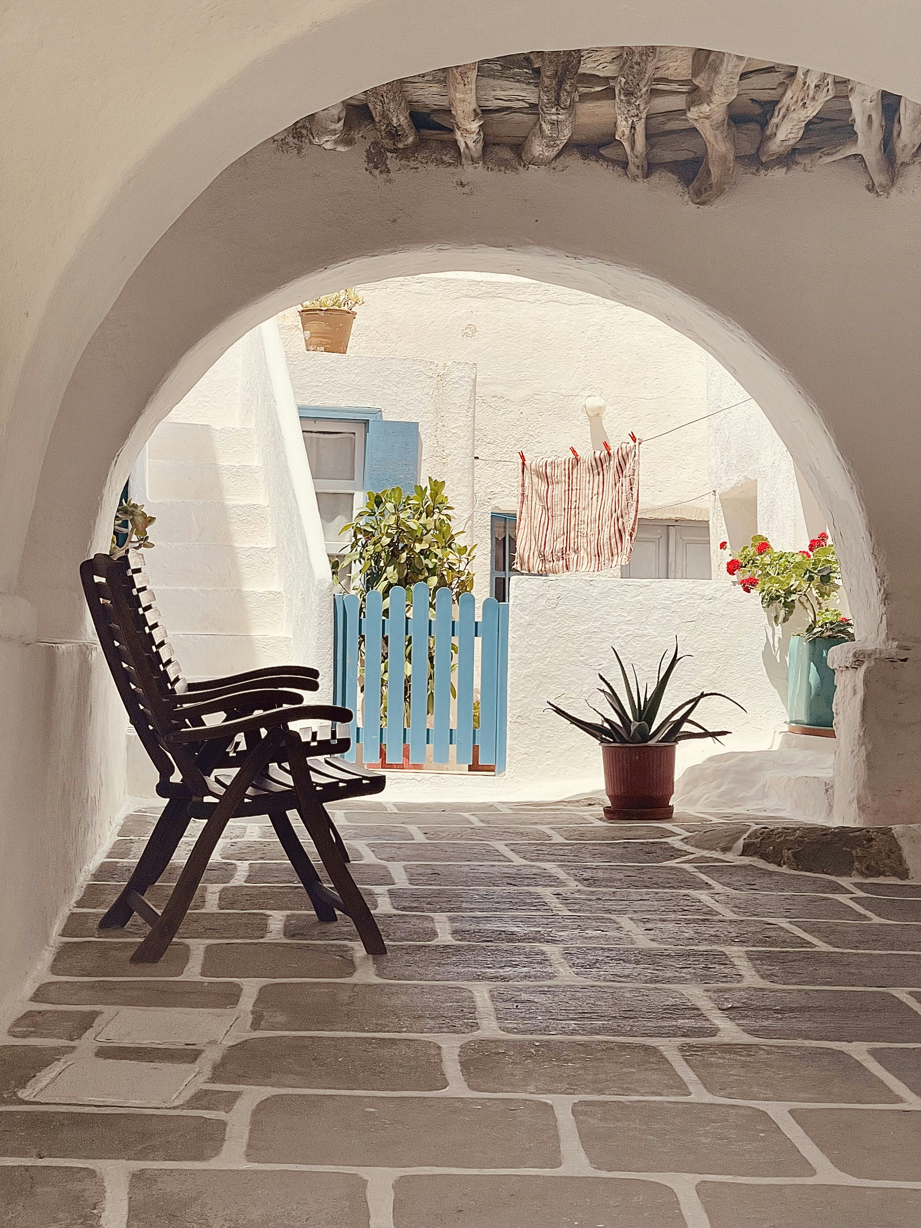 A quiet white lane with blue shutters and bougainvillea in the Chora of Folegandros