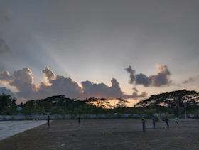A warm, sun-drenched photo of a family playing joyfully in a terracotta-hued field at sunset.