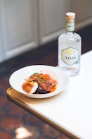a white plate topped with food next to a bottle of alcohol