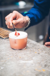 A bartender’s hand delicately placing a fresh herb sprig atop a frothy drink.
