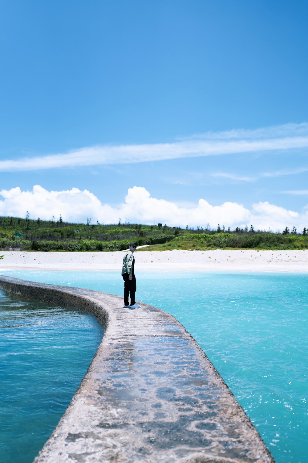 a man standing on a pier next to a body of water