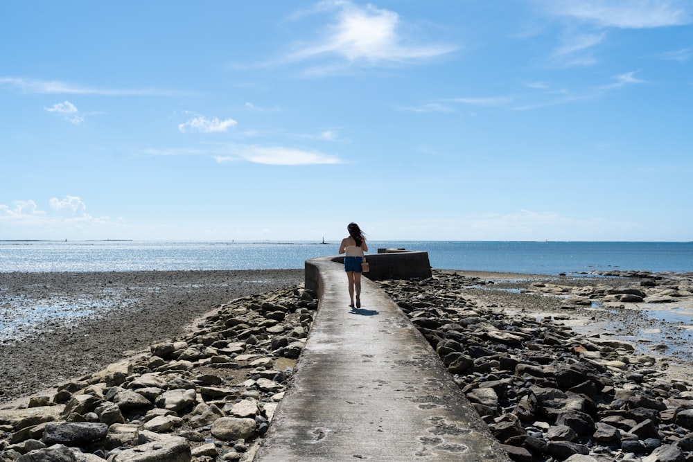 a woman standing on a pier next to the ocean