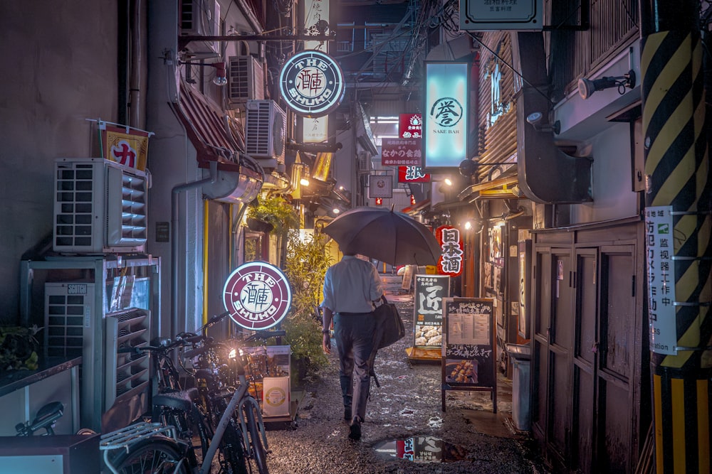 eine Person, die mit einem Regenschirm eine Straße entlang geht