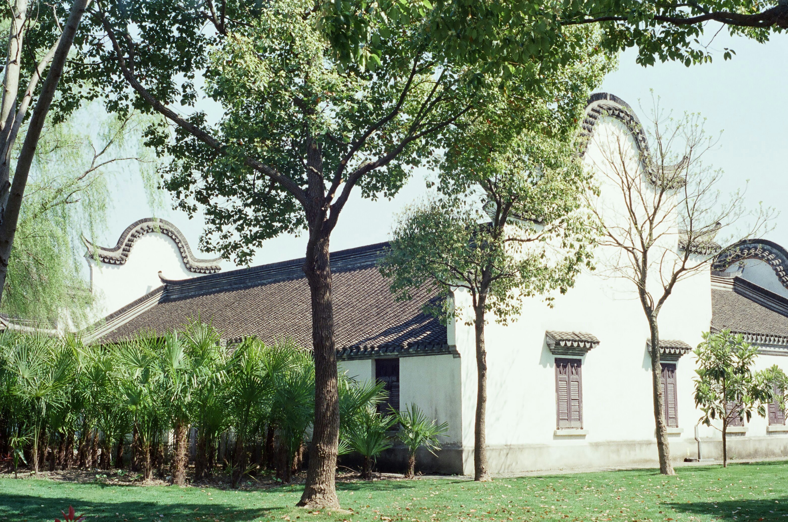 a white building with a black roof surrounded by trees