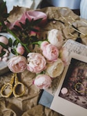 A collection of blush and dusty rose paper goods arranged on a cream-colored linen surface.