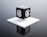 A black cube with a stylized letter 'a' in white on each visible face is placed on a raised white platform. The background is a gradient of gray, giving the scene a modern and minimalist aesthetic.