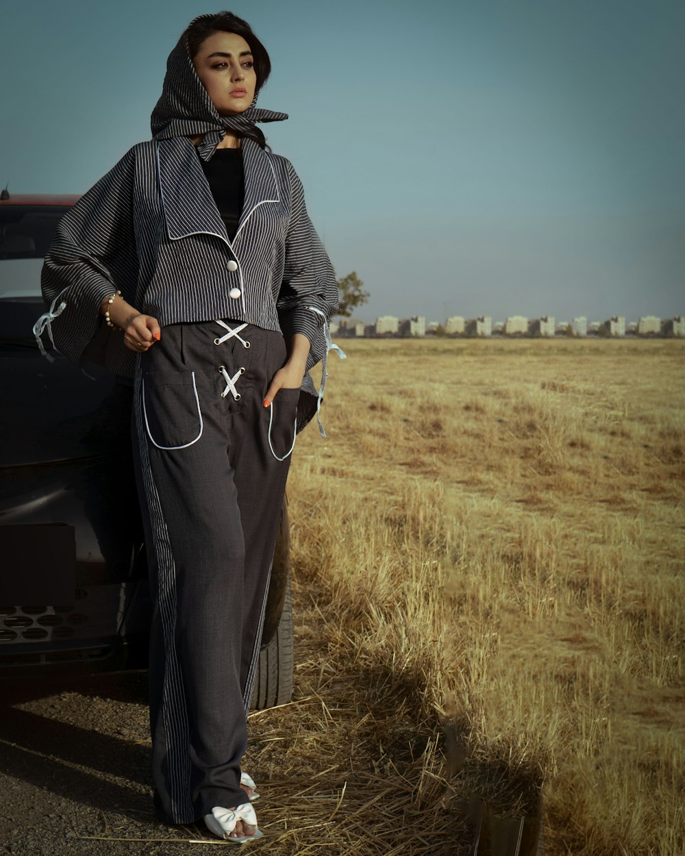 a woman standing next to a car in a field