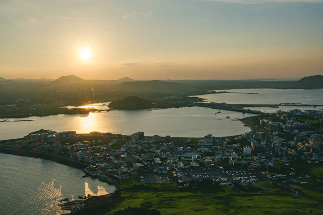 A breathtaking aerial shot of a coastal hotel at sunset with warm golden light reflecting on the water.