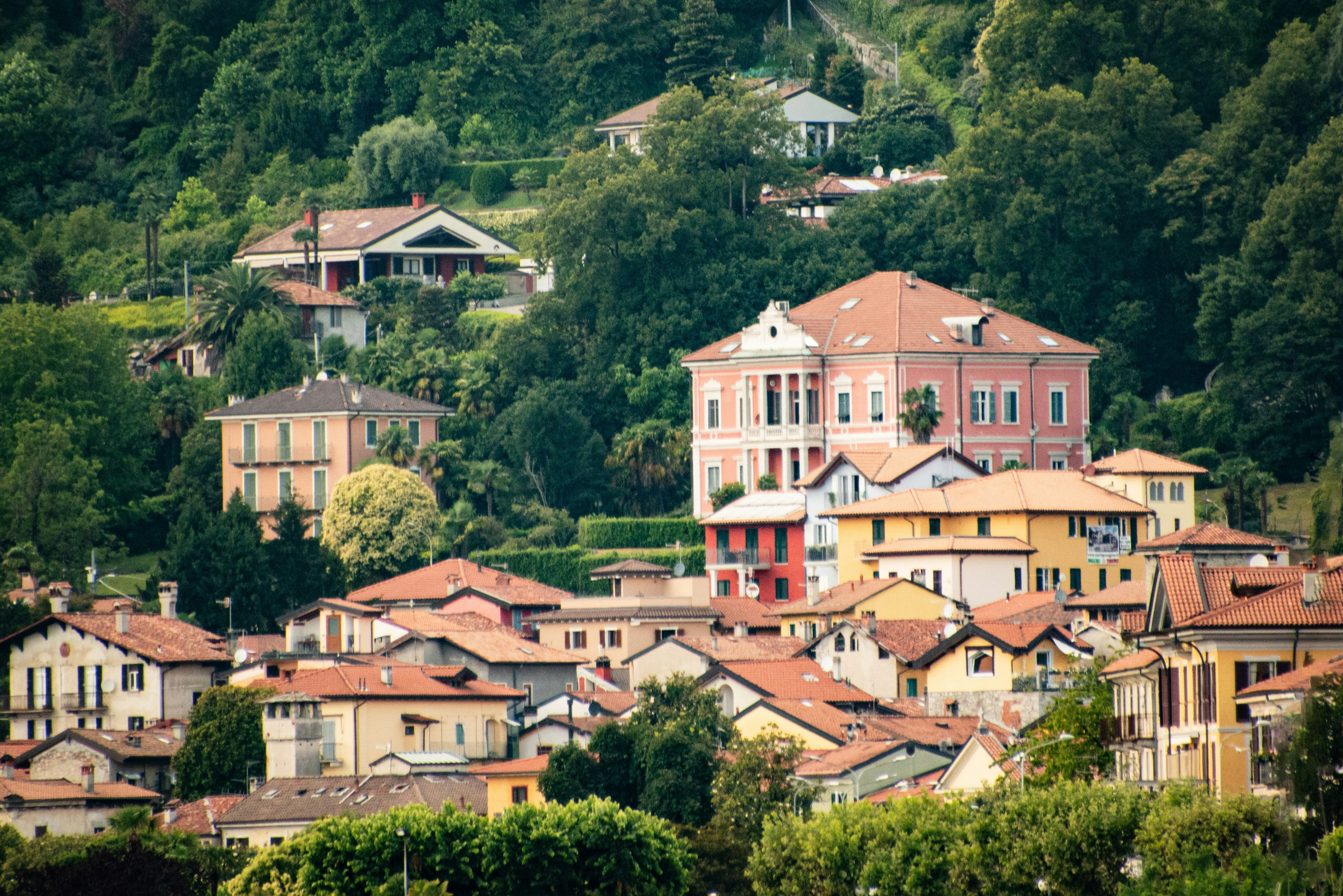 a group of houses on a hillside with trees in the background, 