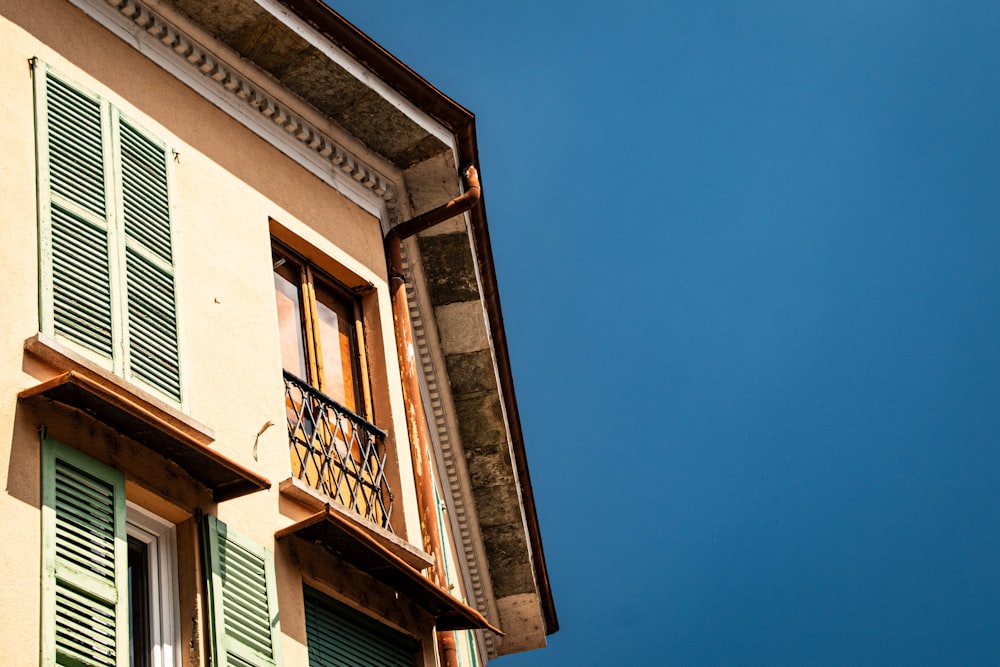 a building with green shutters and a blue sky in the background