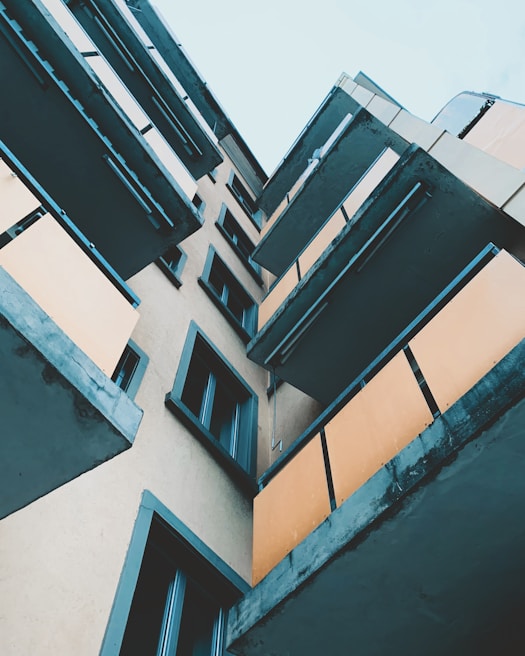 Angular view of a multi-story building with several balconies. The architecture features geometric lines and a modern design. The photo is taken from an upward angle, capturing the layers of balconies and the facade.