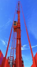 A white and red basket crane extended high with workers safely operating at height.