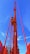 A tall red crane structure extends upward against a bright blue sky. The crane features a control cabin and a ladder for access, prominently highlighted in vibrant colors.
