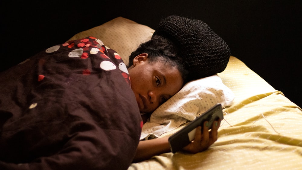 a woman laying in bed with a remote control