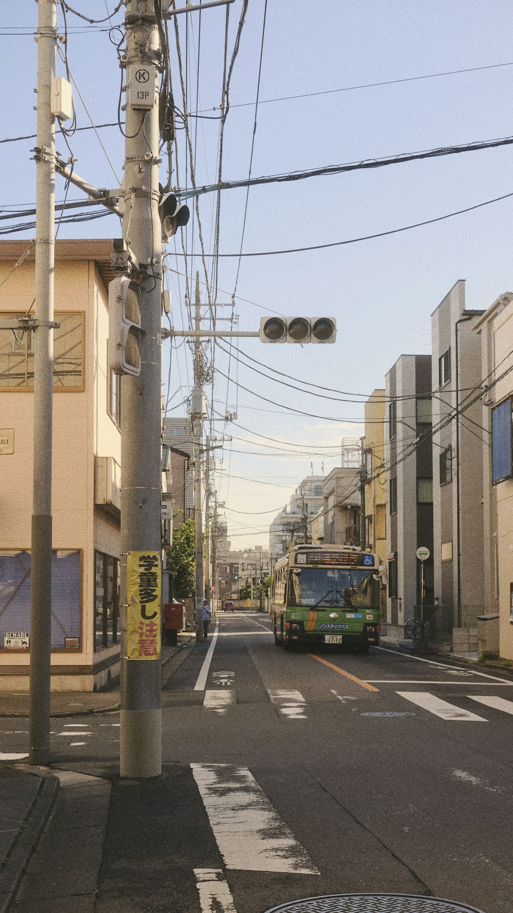 a green bus driving down a street next to tall buildings