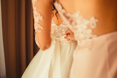 A bride trying on a delicate lace wedding gown in a softly lit boutique.