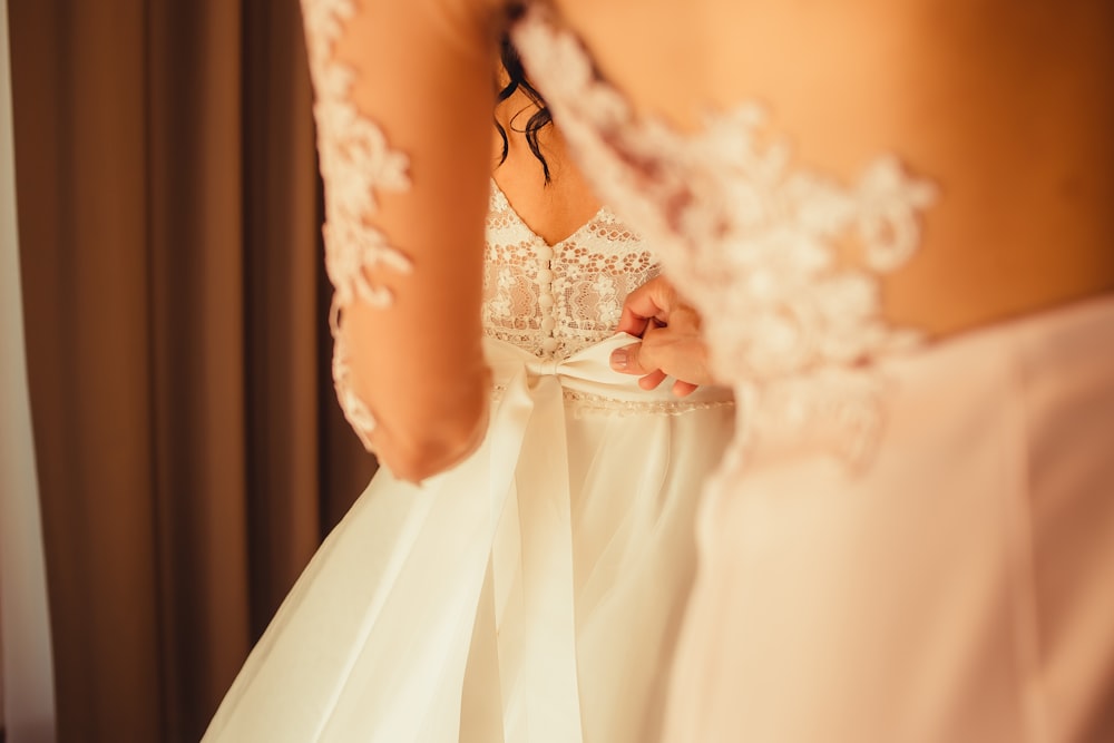 a woman in a wedding dress looking at herself in the mirror
