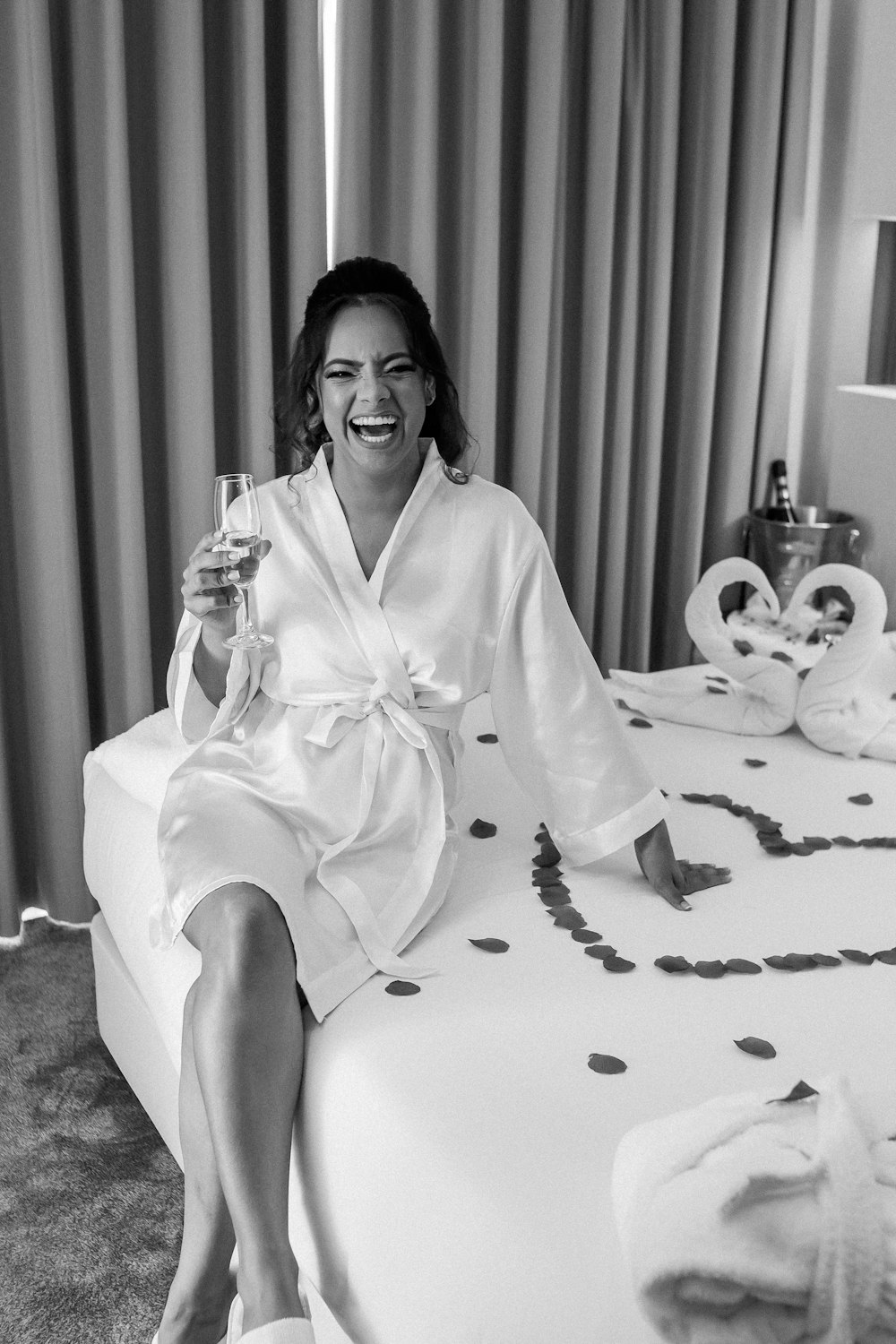 a woman sitting on a bed holding a glass of wine