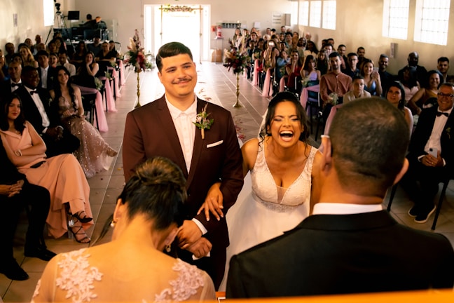A candid shot of the couple laughing under a floral arch during their wedding ceremony.