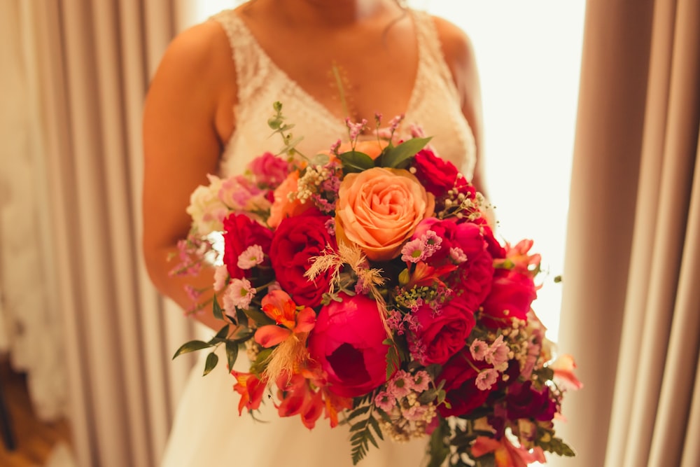 a bride holding a bouquet of red and orange flowers