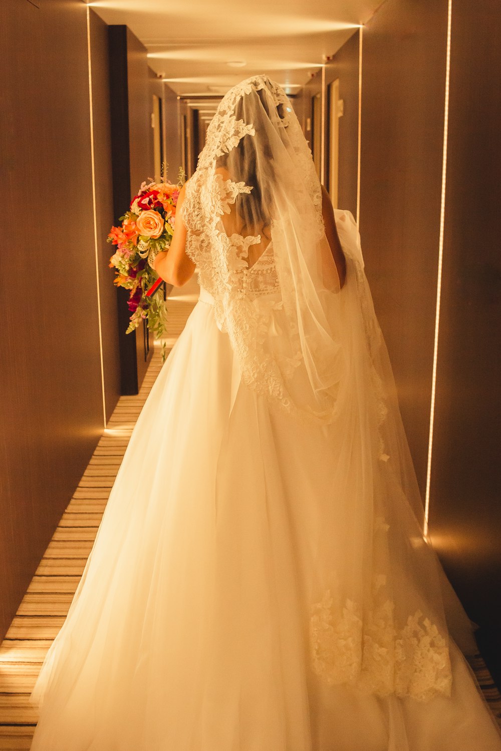 a woman in a wedding dress walking down a hallway