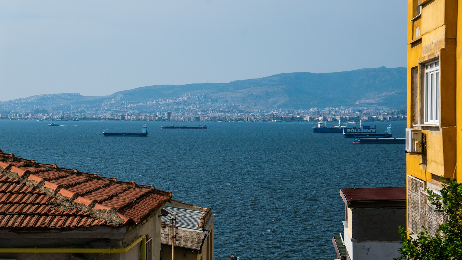 Yamaçtan körfeze bakan konut dokusu, kiremit çatılar ve apartmanlar